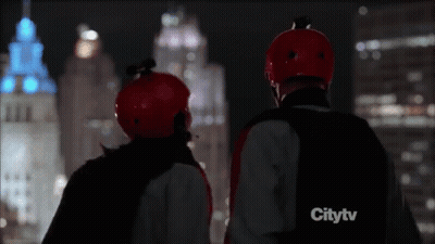 Two People In Red Helmets Watching City At Night GIF