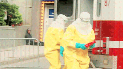 Two People In Yellow Suits Are Standing In Front Of An Ambulance With The Number 87 On The Side GIF