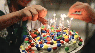 Two People Lighting Birthday Cake With M&Ms GIF