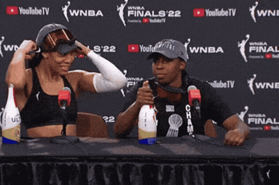 Two People Sitting At A Table In Front Of A Wall That Says Youtubetv GIF