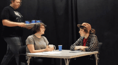Two People Sitting At Table With Man Holding Tray GIF