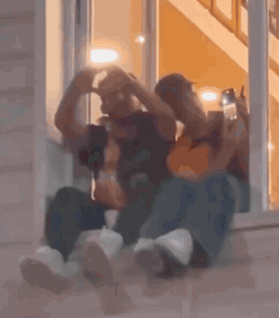 Two People Sitting In Front Of A Door GIF