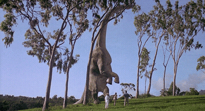 Two People Standing Before Giant Dinosaur GIF
