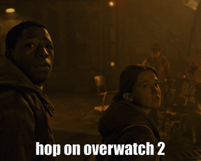Two People Standing In Front Of A Fire With The Words Hop On Overwatch 2 Below Them GIF
