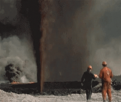 Two People Standing In Front Of A Large Flame GIF