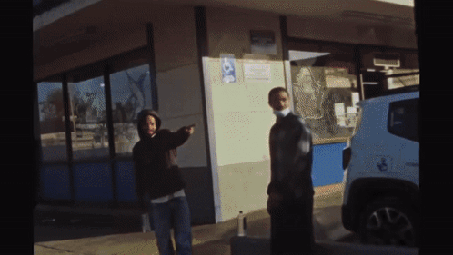Two People Standing Outside Of A Building With A Handicap Sign On The Side GIF