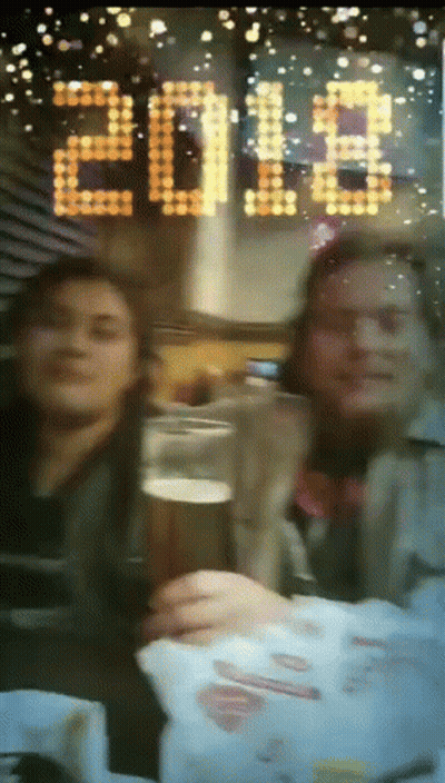 Two People Toasting With A Glass Of Beer In Front Of A Sign That Says 2018 GIF