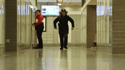 Two People Walking Down A Hallway With A Sign That Says Jojo GIF