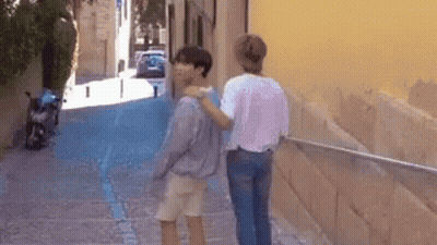 Two People Walking On Narrow Street With Motorcycle GIF