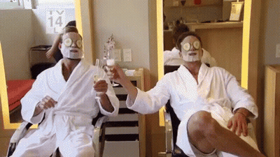 Two People Wearing Facial Masks Are Toasting With Champagne GIF