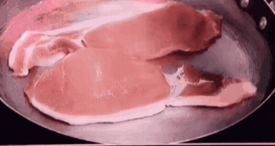 Two Pieces Of Raw Bacon Cooking In A Frying Pan GIF