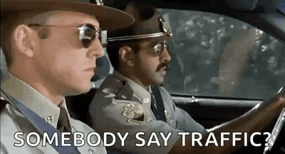 Two Police Officers Are Driving A Car And One Of Them Is Asking Another Police Officer To Say Traffic . GIF