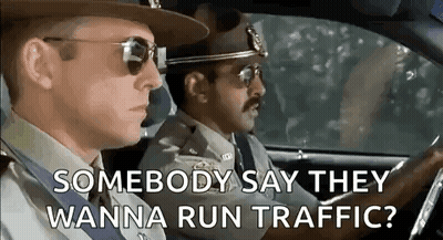 Two Police Officers Are Driving A Car And One Of Them Is Asking The Other If They Wanna Run Traffic . GIF
