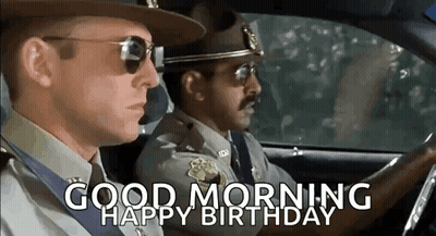 Two Police Officers Are Driving A Car And The Words `` Good Morning Happy Birthday '' Are On The Screen . GIF