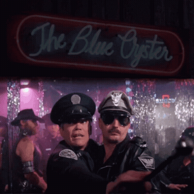 Two Police Officers Are Standing In Front Of A Neon Sign That Says The Blue Oyster GIF