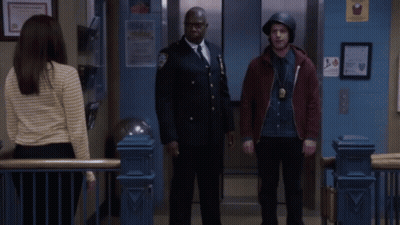 Two Police Officers Giving Each Other A Fist Bump In Front Of An Elevator GIF