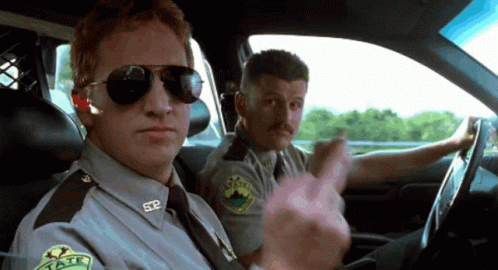 Two Police Officers In A Car With One Wearing A Badge That Says Sdp GIF