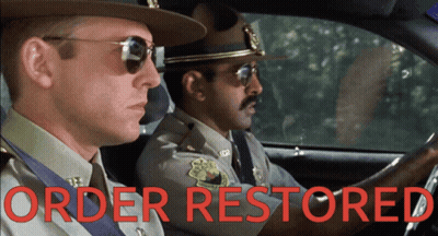 Two Police Officers In A Car With Order Restored Written On The Bottom GIF