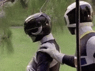 Two Power Rangers Are Standing Next To Each Other On A Field . GIF