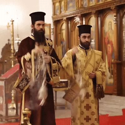 Two Priests Are Standing In A Church And One Of Them Has A Cross On His Robe GIF