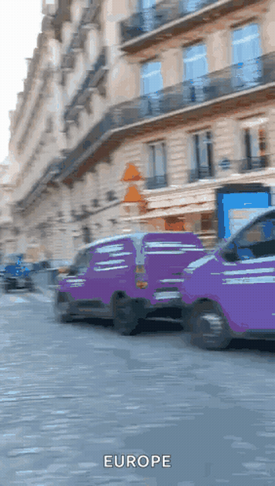 Two Purple Vans Are Driving Down A Street And The Word Europe Is On The Bottom Right GIF