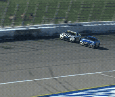Two Race Cars Racing On Track With White Fence GIF
