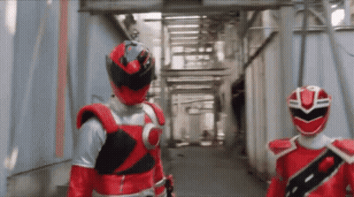 Two Red Rangers Are Walking Down A Hallway GIF