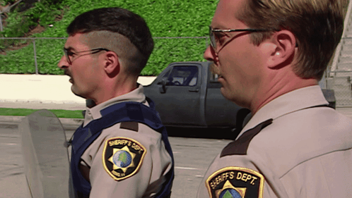 Two Sheriff 'S Deputies Are Standing Next To Each Other In A Parking Lot GIF