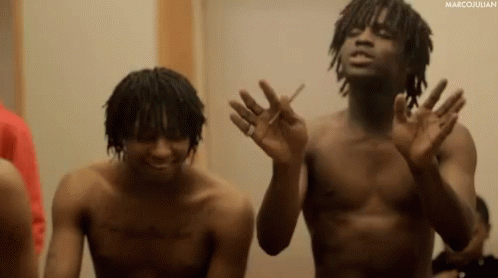 Two Shirtless Men Are Standing Next To Each Other And One Is Smoking A Cigarette GIF