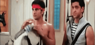 Two Shirtless Men Are Standing Next To Each Other In A Room . One Of The Men Is Wearing A Red Headband . GIF