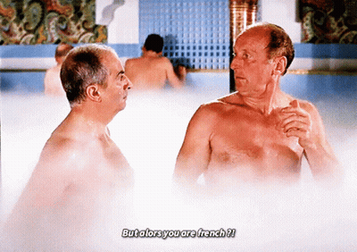 Two Shirtless Men Are Talking In A Bathtub With The Caption But Alors You Are French ? GIF