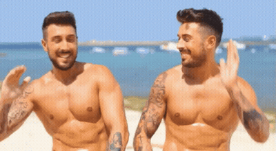 Two Shirtless Men Waving On Beach GIF