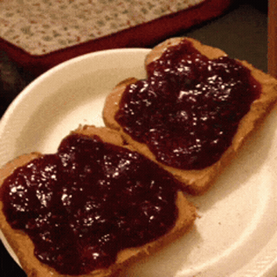 Two Slices Of Peanut Butter And Jelly Toast On A White Plate GIF