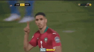 Two Soccer Players Are Celebrating A Goal In Front Of A Large Screen That Says Caf World On It GIF