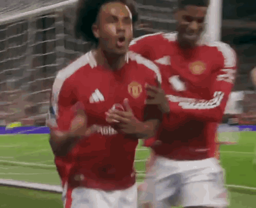 Two Soccer Players Are Celebrating A Goal On The Field . GIF