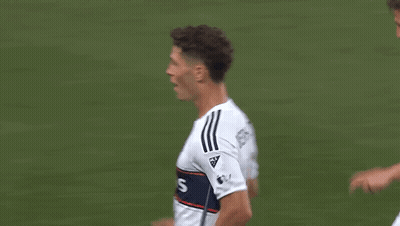 Two Soccer Players Are Celebrating A Goal On The Field While Sitting On The Ground . GIF