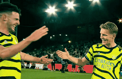 Two Soccer Players Are Giving Each Other A High Five On The Field GIF