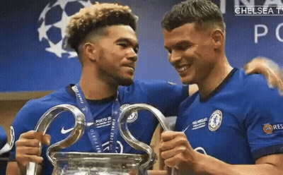 Two Soccer Players Are Holding A Trophy In A Locker Room . GIF
