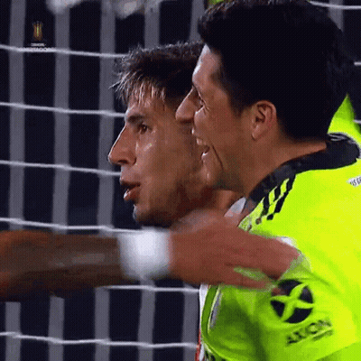 Two Soccer Players Are Hugging Each Other And One Has The Word Axion On His Sleeve GIF