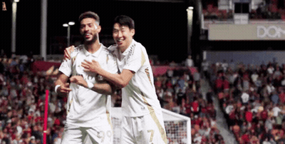 Two Soccer Players Are Hugging Each Other On A Field GIF