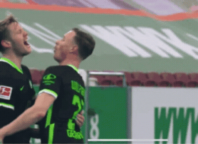Two Soccer Players Are Hugging Each Other On A Field . GIF