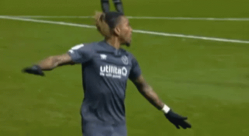 Two Soccer Players Are Hugging Each Other On The Field . GIF