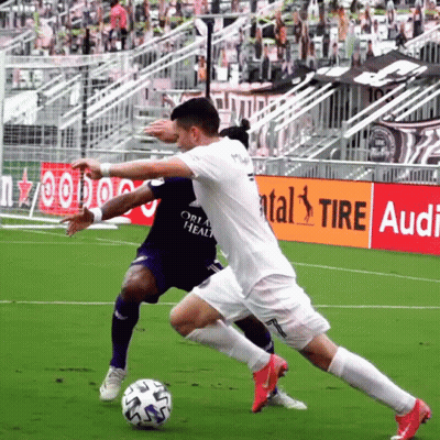 Two Soccer Players Are Playing On A Field With An Audi Ad Behind Them GIF