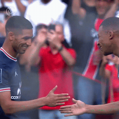 Two Soccer Players Are Shaking Hands In Front Of A Crowd And One Of Their Shirts Says Coor GIF