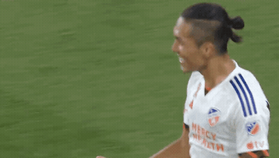 Two Soccer Players Are Shaking Hands On A Field . GIF