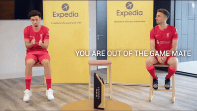 Two Soccer Players Are Sitting In Front Of A Expedia Sign GIF