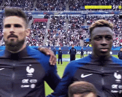 Two Soccer Players Are Standing Next To Each Other On A Field . GIF