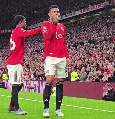 Two Soccer Players Are Standing On A Field With A Crowd Watching . GIF