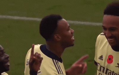 Two Soccer Players Are Talking To Each Other On The Field . One Of The Players Has A Poppy On His Shirt . GIF