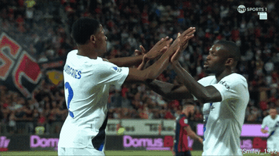 Two Soccer Players High Five In Front Of Domus Banner GIF